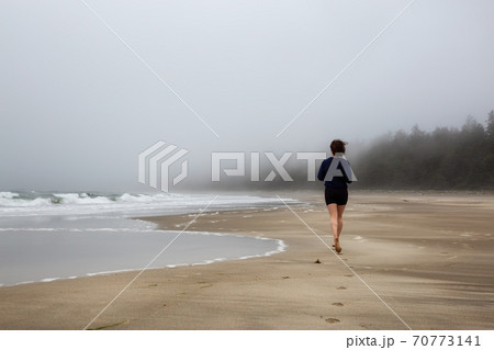 Athletic Caucasian Girl Running on a Sandy Beach near Pacific Ocean Coast Athletic Caucasian Girl Running on a Sandy Beach near Pacific Ocean Coast 70773141