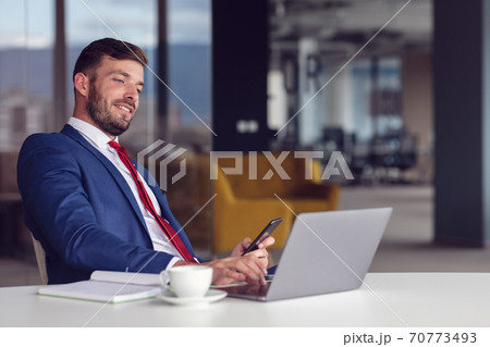 Portrait of young man sitting at his desk in the office Portrait of young man sitting at his desk in the office 70773493