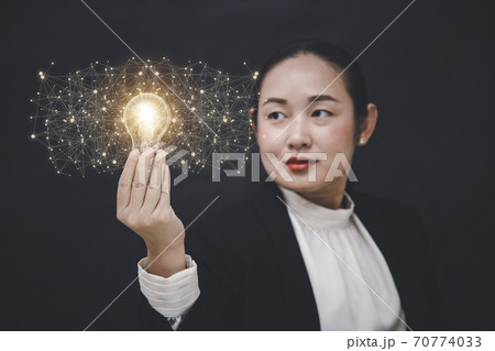 Business Asian woman Holding Illuminated Light Bulb with innovative and creativity are keys to success,innovation and inspiration,ideas and inspiration. concept 70774033