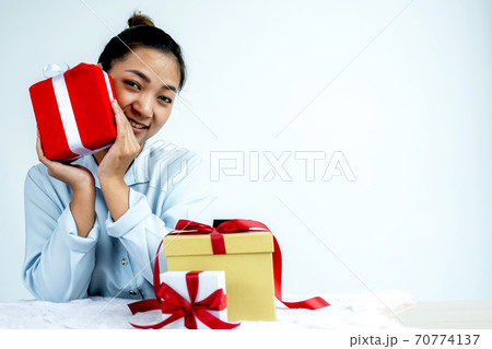 Woman in a blue shirt holding a red gift box tied with a red ribbon present for the festival of giving special holidays like Christmas, Valentine's Day 70774137