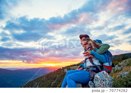 Young Couple Sitting On Top Of Mountain Young Couple Sitting On Top Of Mountain 70774262