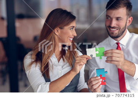 Business people join puzzle pieces in office. Concept of teamwork and partnership. Business people join puzzle pieces in office. Concept of teamwork and partnership. 70774315