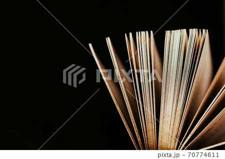 Opened old book with gold pages on a black background, copy space Opened old book with gold pages on a black background, copy space 70774611
