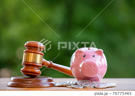 Old wood Judge hammer with Happy Pink piggy Bank in close-up and coins stack the table wood background, Used for adjudication and Justice. 70775465