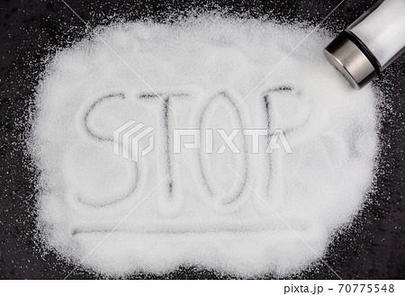 White sea salt for cooking in a small glass bottle. On the salt background, write stop. Concept for health White sea salt for cooking in a small glass bottle. On the salt background, write stop. Concept for health 70775548