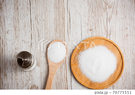 White sea salt for cooking food in Small glass bottles, wooden spoons, and trays on Old wooden table Background. 70775551