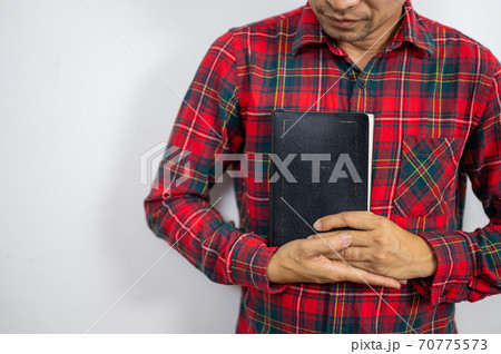 Believer man holding bible book on chest 70775573