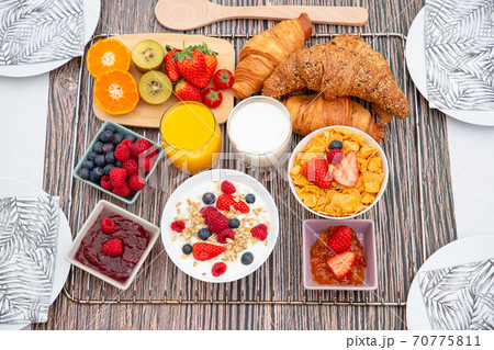 Breakfast Served in the morning with Fruit Yogurt, Butter croissant and corn flakes Whole grains and raisins with milk in cups and Strawberry, Raspberry, Kiwi, Fresh Orange Juice on breakfast table Breakfast Served in the morning with Fruit Yogurt, Butter croissant and corn flakes Whole grains and raisins with milk in cups and Strawberry, Raspberry, Kiwi, Fresh Orange Juice on breakfast table 70775811