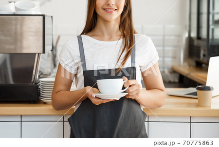 Coffee Business Concept - Caucasian female serving coffee while standing in coffee shop. Focus on female hands placing a cup of coffee. 70775863