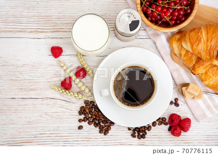 Breakfast in the morning with black coffee cup with bread with Croissant and fruit on the wooden table. 70776115