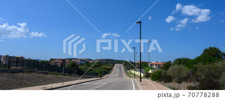 Panorama of road goes into the distance against a blue sky with clouds. On the sides trees and a Panorama of road goes into the distance against a blue sky with clouds. On the sides trees and a 70778288