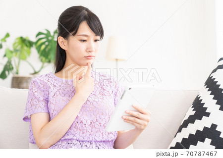 部屋でタブレットを見る女性　考える 70787467