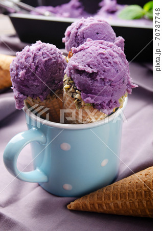 Wafer cones with blackberry icecream in blue mug on wooden kitchen table Wafer cones with blackberry icecream in blue mug on wooden kitchen table 70787748