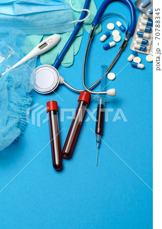 Top view of Medical equipment and tools on blue background - stethoscope, surgical mask, medical gloves, syringe and blood test tube - healthcare and medicine concept 70788345
