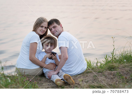 Family sitting near the lake on nature in summer Family sitting near the lake on nature in summer 70788473
