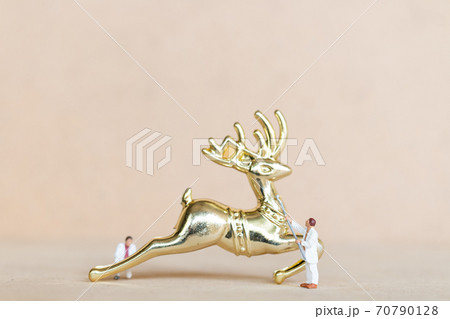 Miniature people,  Worker team painting a Christmas decoration 70790128