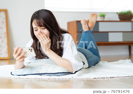 リビングで寝転がりながら動画を見て泣く若い女性 リビングで寝転がりながら動画を見て泣く若い女性 70791470