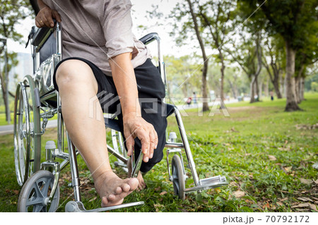 Asian senior woman hand hold nail clippers in wheelchair, female elderly people cutter her toenails or pedicure, trying to reach or bend down to trimmer the nails with difficulty, lifestyle concept 70792172