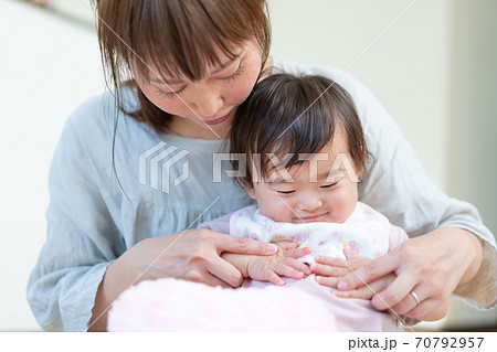 お母さんに抱っこされて笑う赤ちゃんの顔のアップの写真素材