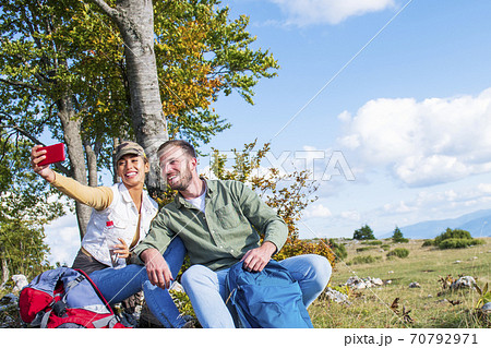 Young couple drinking water while resting on the rock during the travel in the mountains 70792971