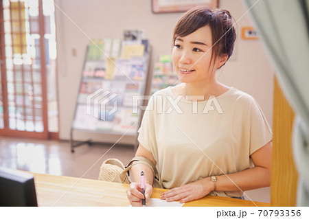 受付で何か書き込む女性 受付で何か書き込む女性 70793356