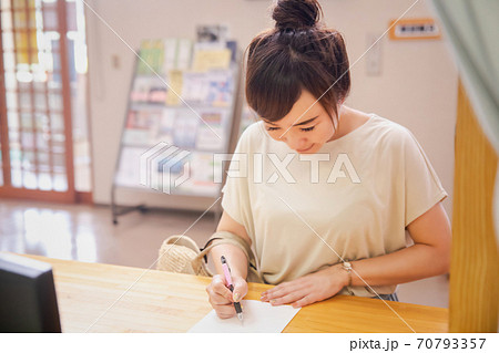 受付で何か書き込む女性 70793357