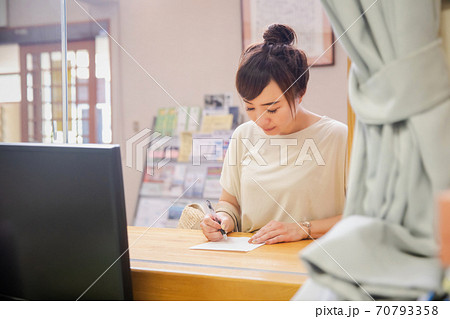 受付で何か書き込む女性 70793358