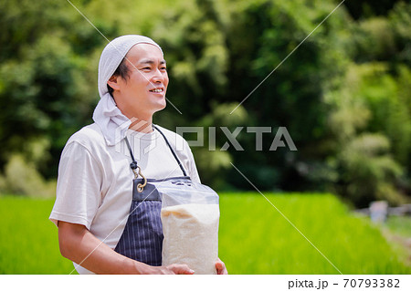 お米を持つ農家 70793382