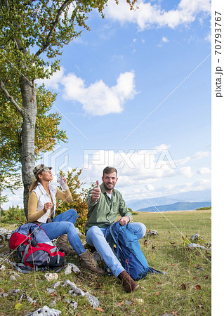 Young couple drinking water while resting on the rock during the travel in the mountains 70793767
