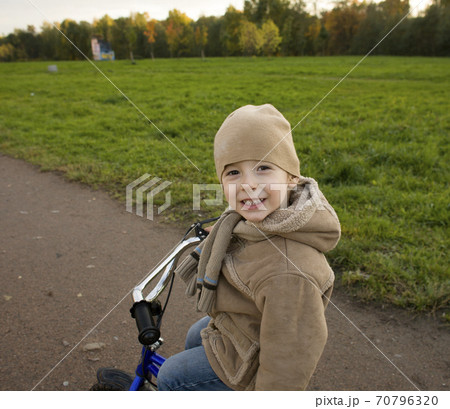 little cute real boy on bicycle emotional smiling close up outside in green amusement park 70796320