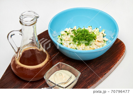 Traditional Russian cold soup with kvass, okroshka with ham, vegetables and sour cream on a wooden board 70796477