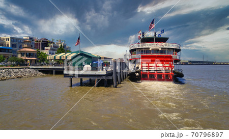Port of New Orleans in Louisiana USA day light view showing The steamboat Natchez on Mississippi River with American flags, Skylines and clouds in the sky in background. 70796897