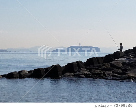 晩秋の湘南茅ヶ崎海岸ヘッドランドで青空の下江の島を眺めながら釣りをする人【11月】 70799536
