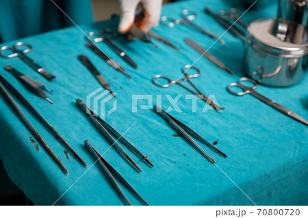 Surgeon hand wear medical gloves choosing surgical instruments on a table in operating room Surgeon hand wear medical gloves choosing surgical instruments on a table in operating room 70800720