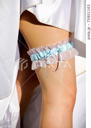 A blue bridal garter on the leg of a young beautiful bride during the wedding A blue bridal garter on the leg of a young beautiful bride during the wedding 70801163