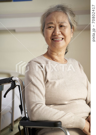 happy senior asian woman sitting in wheel chair in her room in nursing home, happy and smiling 70802417