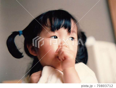 昔のフィルム写真　指をしゃぶる二つ結びの女の子 70803712