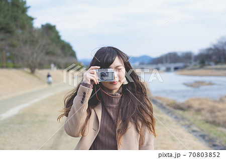 フィルムカメラで写真を撮るロングヘアの女性 フィルムカメラで写真を撮るロングヘアの女性 70803852
