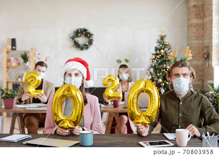 Office workers in protective masks and xmas accessories holding yellow numbers 70803958