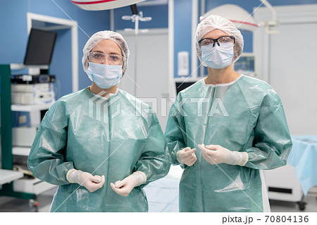Two young professional female surgeons in protective uniform, gloves, mask, etc 70804136