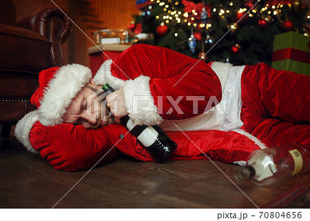 Vile drunk Santa claus sleeps under christmas tree 70804656