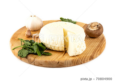 Round soft cheese, parsley, garlic and mushroom on a wooden cutting board. 70804900