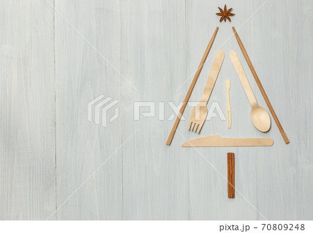 Layout in the form of a Christmas tree made of wooden Cutlery. On a light wooden background, top view, horizontally with space Layout in the form of a Christmas tree made of wooden Cutlery. On a light wooden background, top view, horizontally with space 70809248