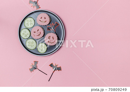 Appetizer for a Halloween party. A plate of ham Sandwiches with scary faces cut out. Top view on a pink background with space Appetizer for a Halloween party. A plate of ham Sandwiches with scary faces cut out. Top view on a pink background with space 70809249