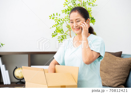 荷物が届く　お礼の電話をかけるシニア女性 70812421