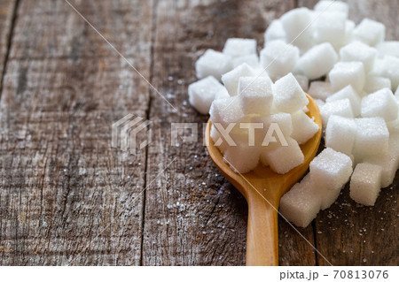 Sugars cube in wooden spoon over wooden background. Sugars cube in wooden spoon over wooden background. 70813076