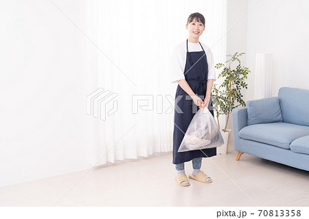ゴミ袋を両手で持つ若い女性 70813358