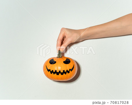 Hand holds halloween pumpkin on white wall 70817028