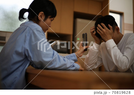 男性にスマートフォンの画面を見せる女性 男性にスマートフォンの画面を見せる女性 70819628