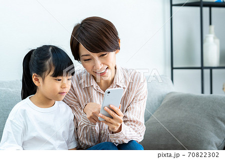 リビングでスマホを見ながら寛ぐ親子（母子） 70822302